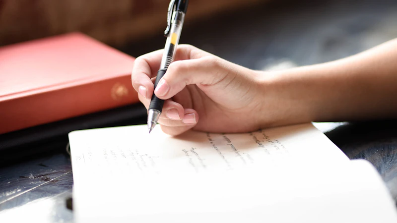 Person writing on paper with a pen