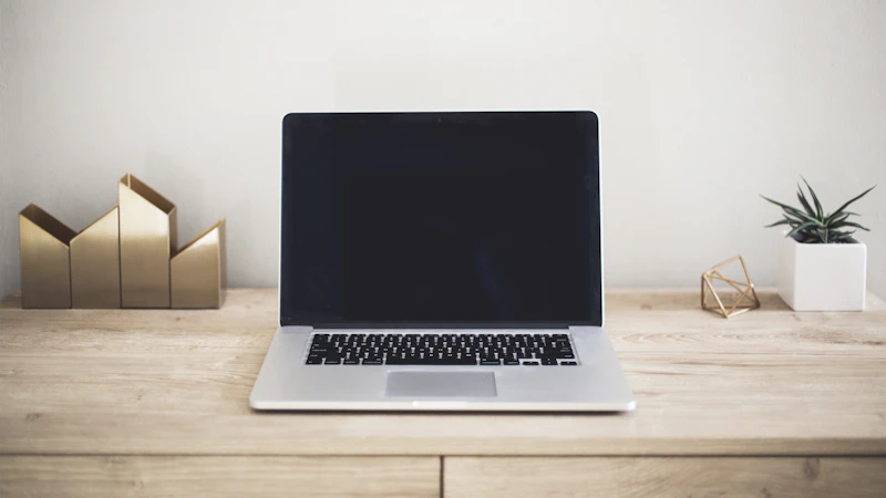 Open silver laptop with a dark widescreen display on a wooden desk
